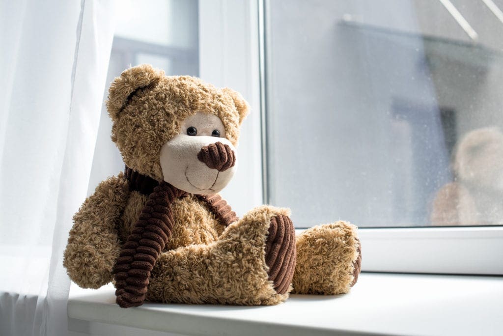 Un adorable ours en peluche sur un rebord de fenêtre vide.