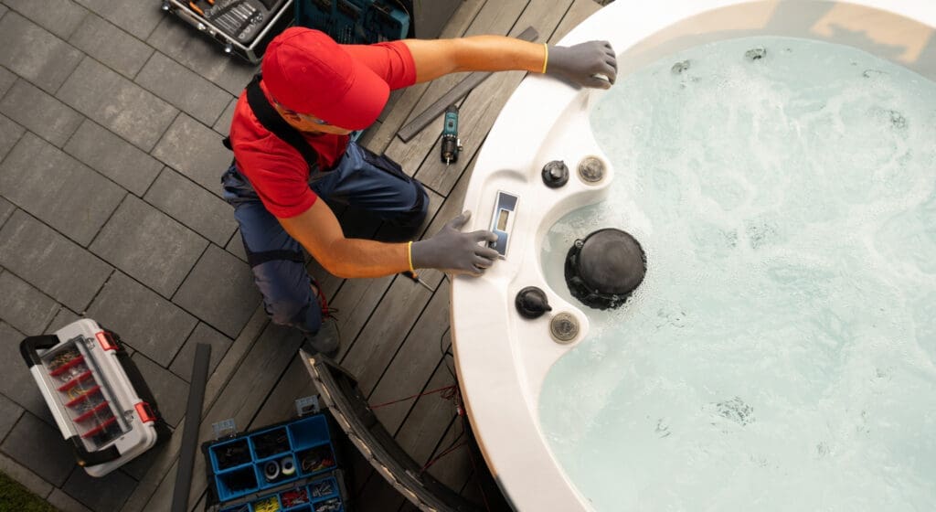A technician adjusts the control panel of a hot tub during a maintenance check, preparing for safe relocation.