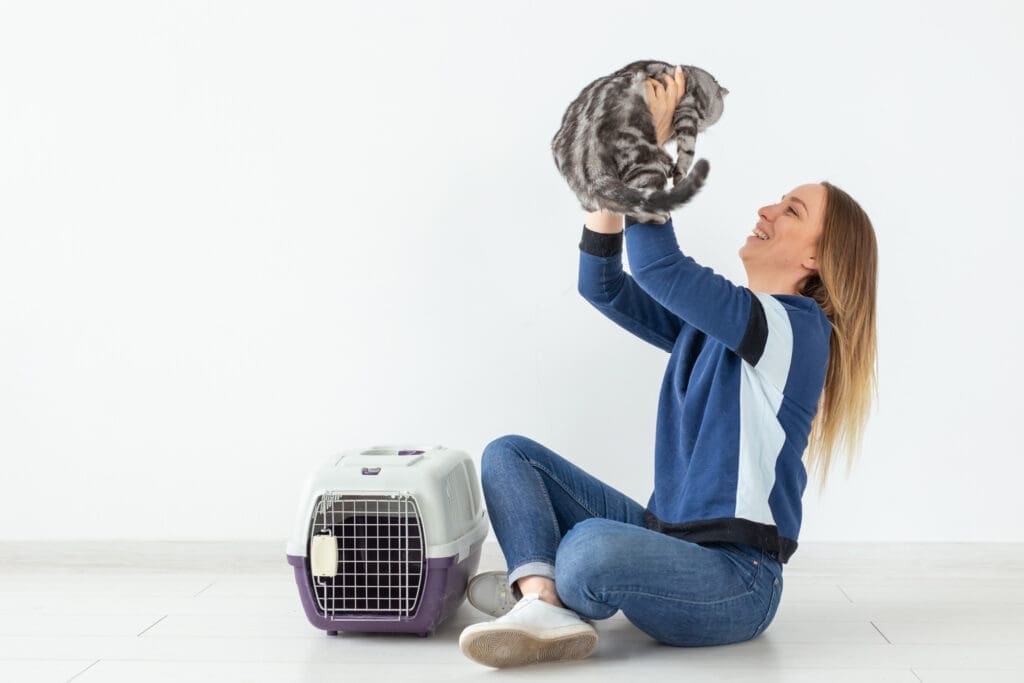 oman holding a cat near a pet carrier